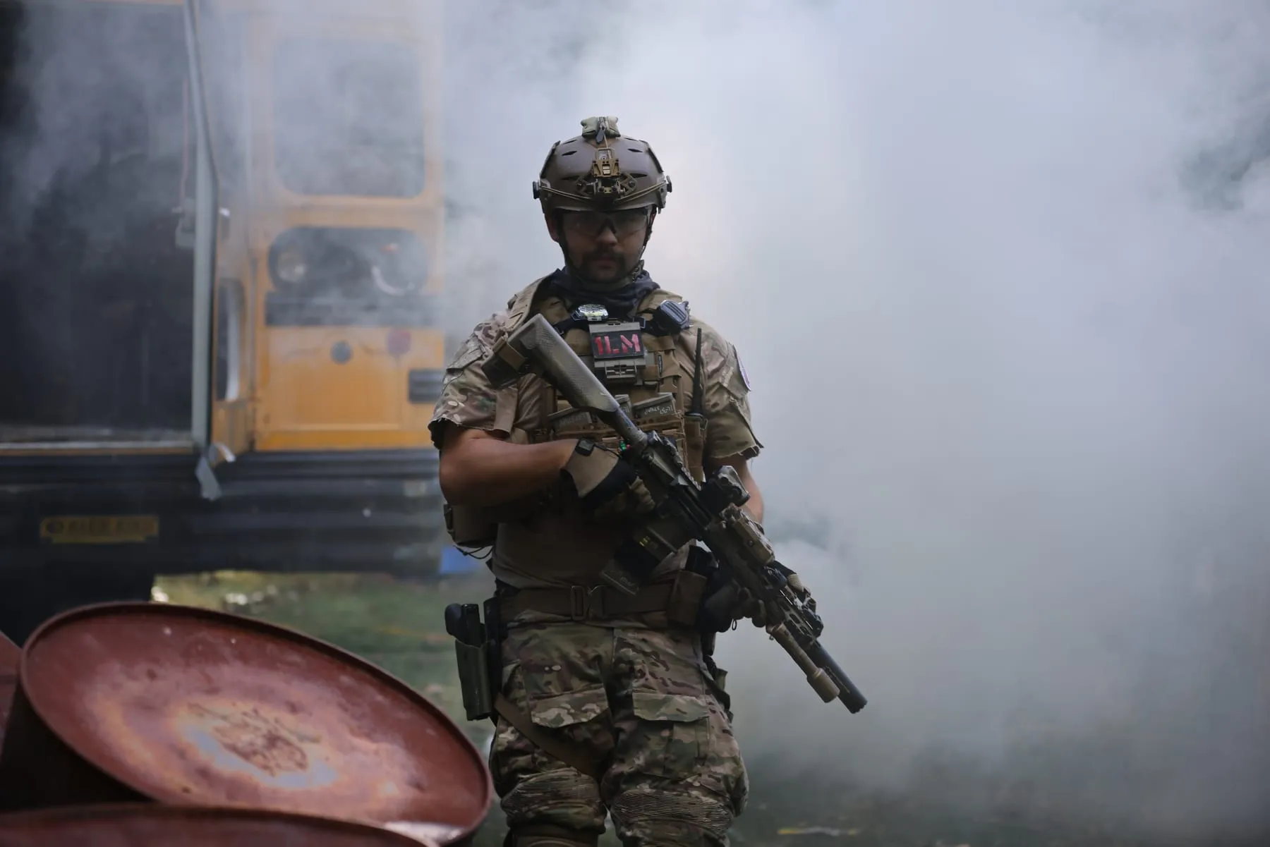 Player holding his rifle in front of a smoke-filled bus